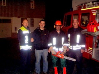 Wehrführer Tobias Hiebsch, Geschäftsinhaber Hans-Werner Parske, Roger Zaschke mit Säge und Schutzkleidung sowie stellvertretender Wehrführer Michael Pelz (v.l.).tw.