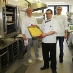 Der stellvertretende Küchenleiter Thomas Grimm (mitte) holt die fertigen Kartoffeln aus dem Ofen. Im Hintergrund: Küchenleiter Walter Ide (links) und Auszubildender Arthur. Foto: tw
