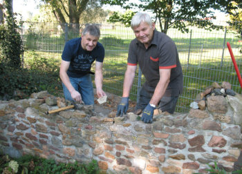 Armin Teuchler und Albert Blaschke mauerten über 60 Steine von Wallfahrern in die Pilgermauer an der Trutzhainer Wallfahrtskirche ein. Foto: Wolfgang Scholz