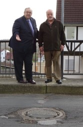 Bernd Siebert MdB und Ortsvorsteher Klaus Dieter Mirswa vor einem abgesenkten Kanaldeckel mitten auf der Fahrbahn. Foto: nh