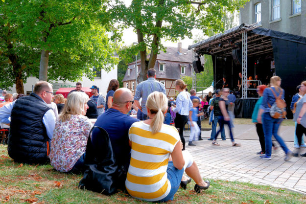 Schattiges Plätzchen: Unter den Bäumen neben der Hephata-Kirche können Besucher ganz entspannt dem Programm auf der Biodorf-Bühne lauschen. Foto: Stefan Betzler | Hephata