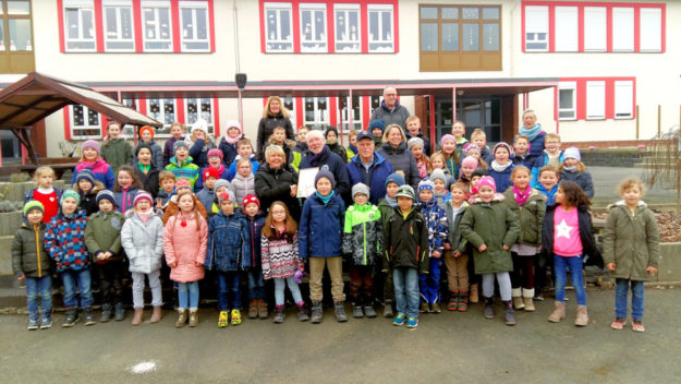 Gruppenbild mit Kindern der drei Grundschulklassen bei Überreichung der Urkunde für die 3. Klasse. In der Bildmitte stehen (v.li.) Gabriele Landsiedel, Hans-Dieter Nitsch, Heinz Marx und Susan Stürzenbecher. Foto: nh