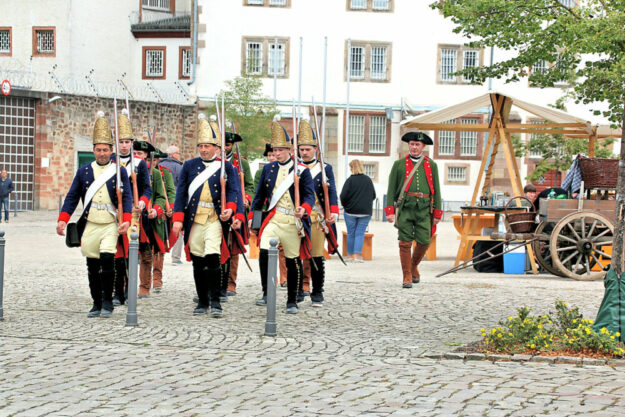 Ein Hingucker: Soldaten marschieren auf dem Ziegenhainer Paradeplatz. Aribert Ley (re. in grün-rotem Kostüm) hält am Samstag einen Vortrag zu den Dreharbeiten zum Film „Der Winter, der ein Sommer war“. Foto: Gerhard Reidt | Schwalmfoto