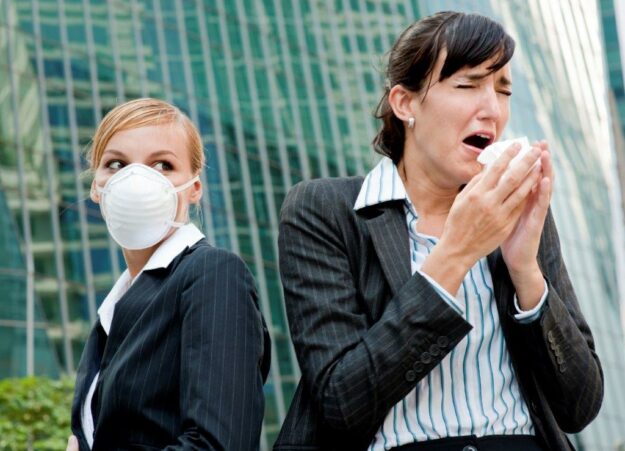 Büroangestellte mit Taschentuch und Maske – die Viren sind inzwischen omnipräsent. Foto: DAK Gesundheit