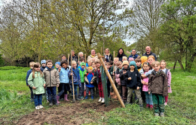Mit Unterstützung durch Bauhofmitarbeiter Karsten Menzel und Naturparkführerin Monika Faupel pflanzen die Grundschulkinder die Bäume des Jahres. Foto: N.N. | Stadt Gudensberg