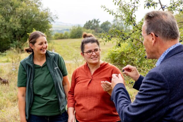 Die Projektmanagerinnen Annika Ludolph (Naturpark Habichtswald) und Manuela Greipel (Naturpark Reinhardswald) pflücken gemeinsam mit Burkhard Weinbrenner von der Volksbank Kassel-Göttingen einige der tiefblauen Beeren der Schlehe vom typisch dornigen Astwerk. Foto [CC BY SA]: Carolin Ludwig | Volksbank Kassel-Göttingen